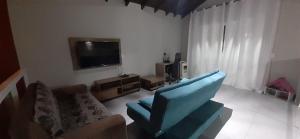a living room with a blue chair and a television at A Casa TOP da Região in Matinhos