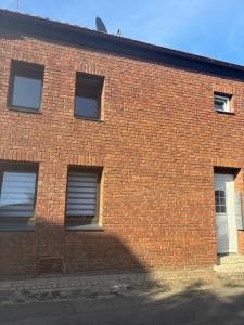 a brick building with three windows and a white door at Monteurwohnung-Ferienapartment in Euskirchen