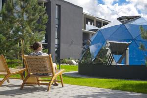 a woman sitting in a chair in front of a building at Balimood Stay in Palanga