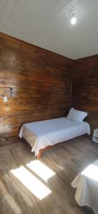 a bedroom with two beds in a wooden wall at Chalé Mirante do Salto in Rio Forcação