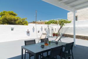 a table and chairs on a patio with a white wall at Θεμωνιά house in Káto Petálion