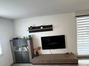Una sala de estar con un televisor de pantalla plana en una pared. en Appartement 50m2 Amnéville avec balcon à 2 min des thermes, en Amnéville 6 fotos más