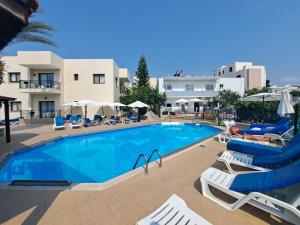 a large swimming pool with lounge chairs and umbrellas at C & A Hotel Apartments in Polis Chrysochous