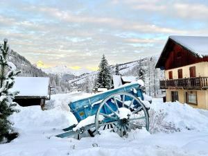 un mulino coperto di neve, adagiato nella neve accanto a un edificio di Casa-Le Toussiard apart dans chalet St-Véran 4-6p a La Chalp-Sainte-Agathe Altre 22 foto