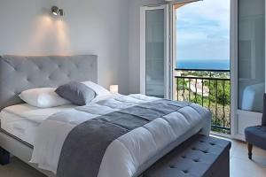 une chambre avec un grand lit et une grande fenêtre dans l'établissement CASA-Capussambre spacious villa with sea view heated pool air con sauna Les Issambres, aux Issambres