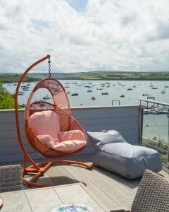 a swinging chair on a balcony with a view of the water at FERRYPOINT - 3 Bed Stylish Beachfront Retreat in Padstow