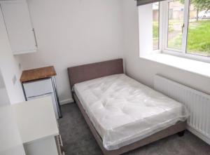 a bed sitting in a room with a window at City breaks Corby Uist Walk in Rockingham