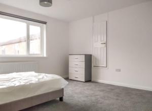 a bedroom with a bed and a dresser and a window at City breaks Corby Uist Walk in Rockingham