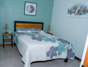 Un dormitorio con una cama con una pared azul. en Mi Barrio, en Cartago