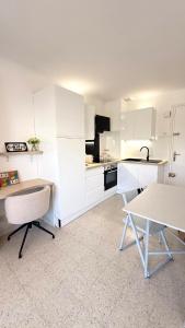 a kitchen with white cabinets and a table and chairs at Entre Ciel&Mer in Palavas-les-Flots
