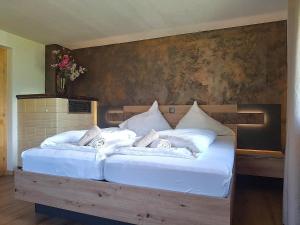 a large bed with white sheets and pillows on it at Alpenfeder Hüsli in Tschagguns