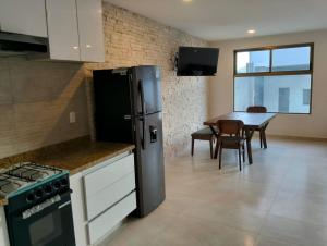 a kitchen with a refrigerator and a table with chairs at Nuevos departamentos en Valle de Bravo in Valle de Bravo