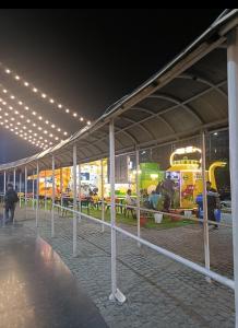 Un grupo de mesas y sillas debajo de un edificio con luces. en Darshana Studios#Cozy, en Noida