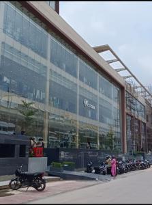 un gran edificio de cristal con motocicletas estacionadas frente a él en Darshana Studios#Cozy, en Noida
