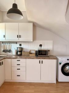 a kitchen with white cabinets and a microwave at Mimosa House in Gythio