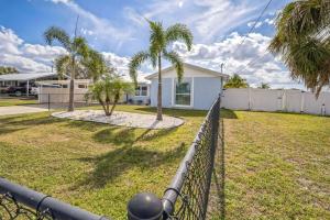 a fence in front of a yard with palm trees at Apollo Beach Retreat - 3BR - Pool - Backyard -BBQ in Apollo Beach