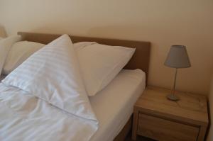 a bed with white pillows and a table with a lamp at Domki letniskowe PLUSK in Drawno