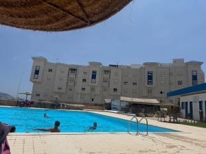 a swimming pool in front of a large building at Résidence BAB Sebta apartment Ghali in Fnidek