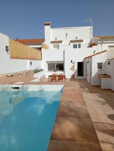 a white house with a swimming pool in front of it at Casa Rural la Sierra del Viento in Guadalcanal
