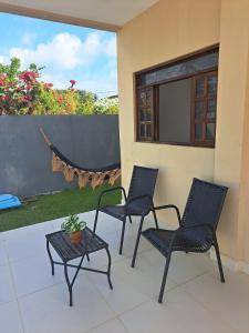 three chairs and a table on a patio at Charmosa Casa de Praia in Pitimbu +2 photos