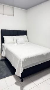 a bed with a black frame and white sheets at Mami yola 2 in Valledupar