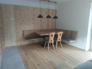 a dining room with a wooden table and two chairs at Mitterhofer Appartements in Villandro +7 photos