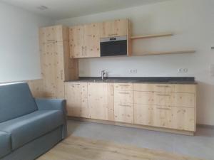 a kitchen with wooden cabinets and a couch and a microwave at Mitterhofer Appartements in Villandro