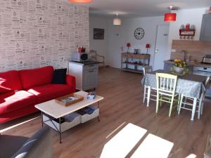 a living room with a red couch and a table at La grange aux oiseaux in Beaulieu