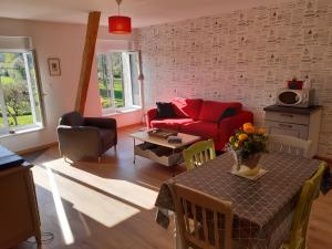 a living room with a red couch and a table at La grange aux oiseaux in Beaulieu