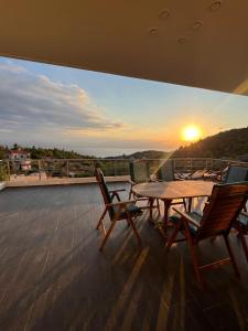 a table and chairs on a deck with the sunset at White Sand Loutraki Villa - Sea View in Loutraki