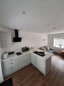 a kitchen with white cabinets and a living room at Woodpeckers Annexe in Gosfield in Gosfield