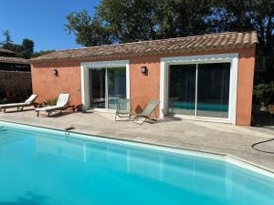a swimming pool with two chairs and a house at Guest house Maison d'invités in Le Rouret