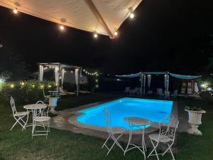 a swimming pool at night with chairs and a table at Casale I Tigli in Lucca