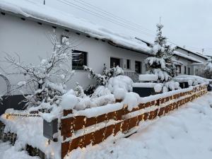 a house covered in snow next to a fence at FeWo Riegel - Allgäu nah an A7 & Legoland in Illertissen +28 photos
