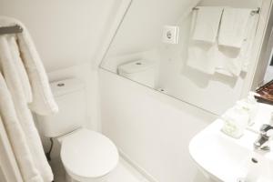 a white bathroom with a toilet and a mirror at FixingInn in Santa Isabel in Lisbon +20 photos