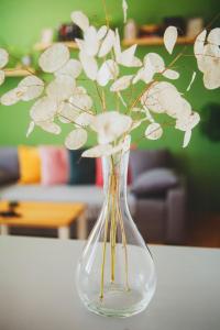 a glass vase with white flowers in it on a table at Boho Harmony Apartment in Rača +9 photos