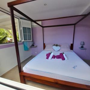 una camera da letto con un letto con lenzuola bianche e pareti viola di Janelle a Le Diamant