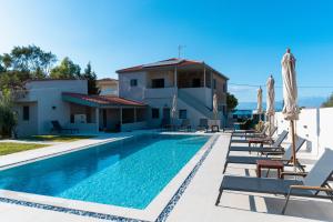 a pool with chairs and umbrellas next to a house at Ollenia's Harmony Luxury Apartments in Derveni