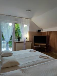 a bedroom with a large white bed and a television at Pensjonat Jaśmin in Ustka
