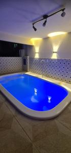 uma grande banheira azul num quarto com luzes em Apartamento perto de praia Dos Anjos em Arraial do Cabo