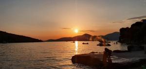 a sunset on a lake with boats in the water at Aqua Apartments in Bigovo +12 photos