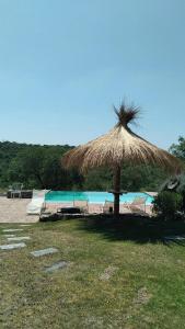 a straw umbrella on a beach with a pool at CuyenCo in Santa Rosa de Calamuchita