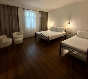 a hotel room with two beds and a chair at The Stone Arch Inn in Gjirokastër