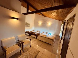a bedroom with two beds and chairs in a room at Calmaria Suítes Búzios in Búzios