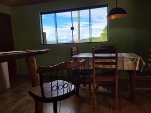 a dining room with a table and chairs and a window at Chalé Vista do Vale Cangalha in Aiuruoca