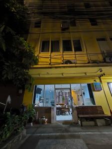 een geel gebouw met een bank ervoor bij Santo house Bangkok in Bangkok