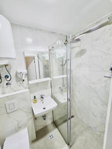 a white bathroom with a shower and a sink at AMARIS Suites Sarajevo in Sarajevo +41 photos