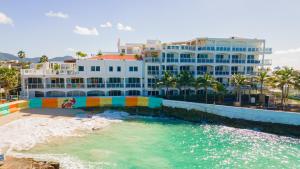 a large white building with a swimming pool next to a beach at Maho Beach Beautiful Garden Studio in Maho Reef