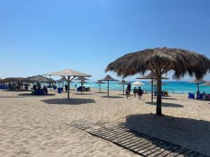 a beach with umbrellas and people on the beach at Dimora Village Challet in Dawwār Muḩammad Abū Shunaynah