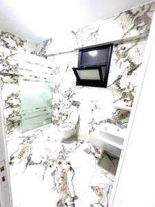 une salle de bain avec toilettes et un mur en marbre dans l'établissement Mohamed Home, à Jazīrat al ‘Awwāmīyah